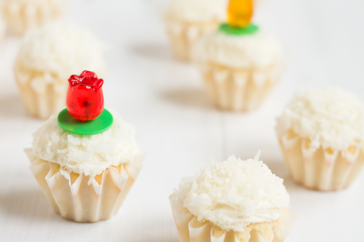 Coconut cupcakes with coconut buttercream and coconut topping, with tulip-shaped ring pops for decoration.
