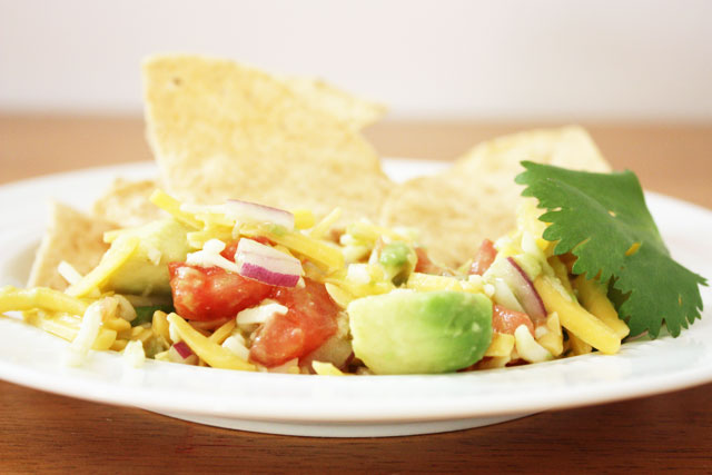 This super fresh tex-mex dip is unlike anything else I've ever had. Fresh avocado, red onion, and tomatoes combine with shredded cheese and a hint of green taco sauce to make a delicious dip.