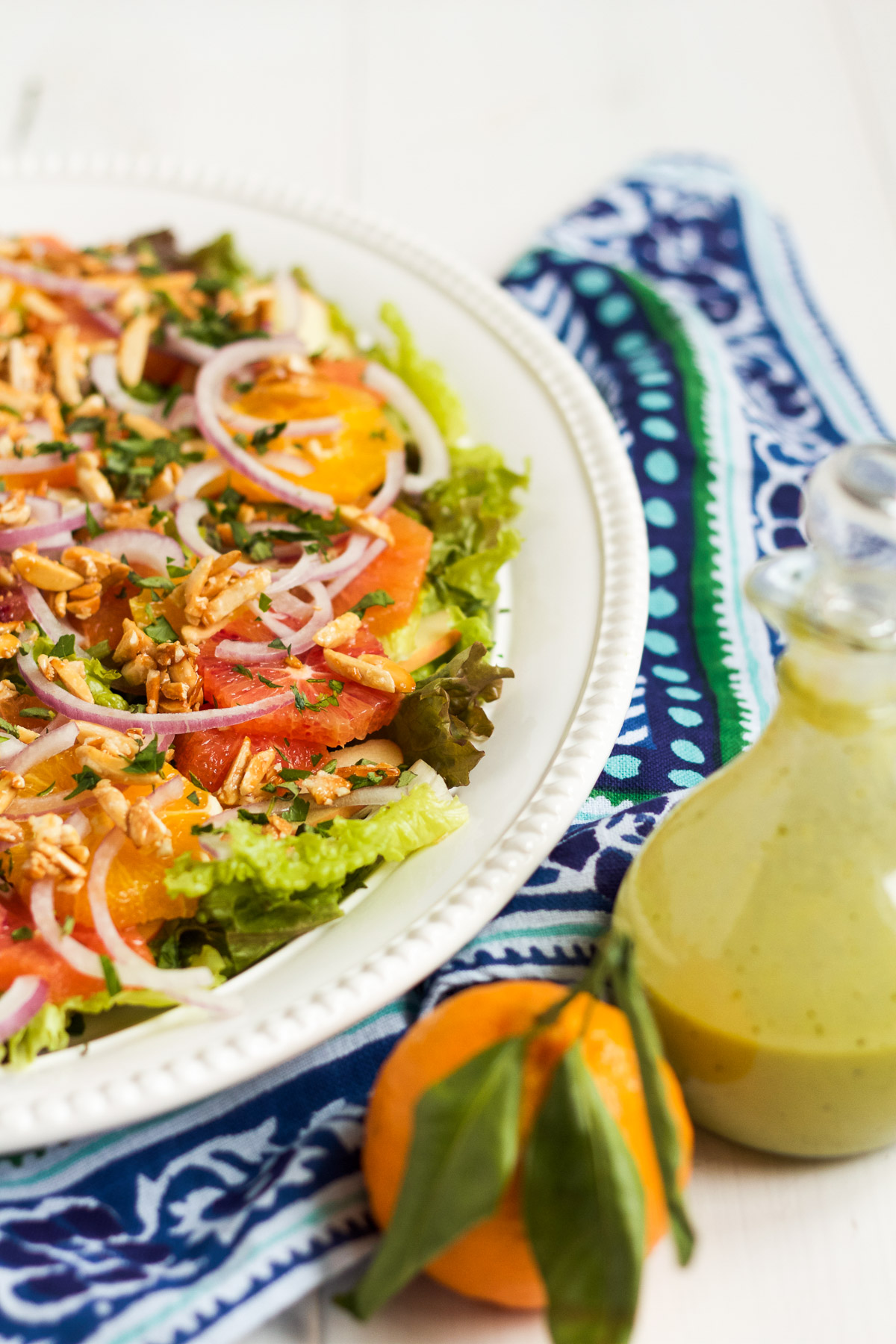 This salad is a family favorite! Tender red leaf lettuce salad is topped with thinly sliced apples, fresh oranges, red onions, and homemade sugared almonds, with an herby, from-scratch vinaigrette to top it all off.