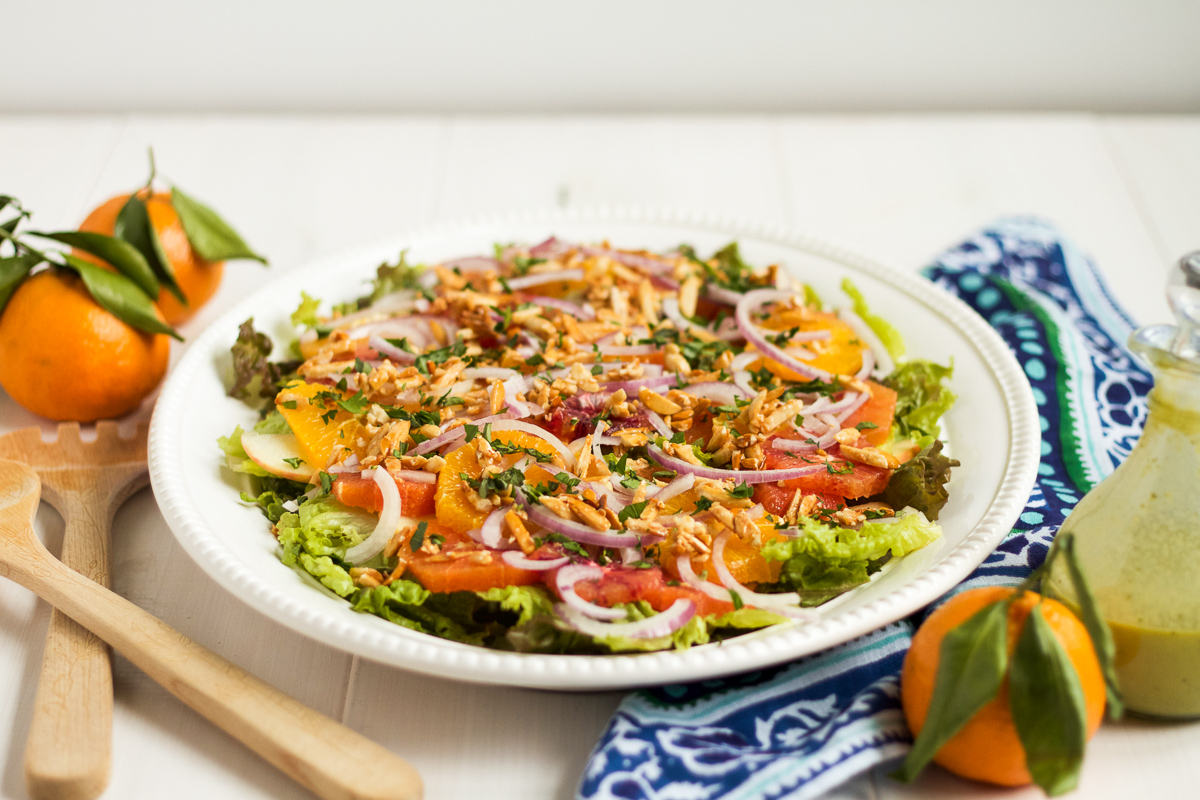 This salad is a family favorite! Tender red leaf lettuce salad is topped with thinly sliced apples, fresh oranges, red onions, and homemade sugared almonds, with an herby, from-scratch vinaigrette to top it all off.