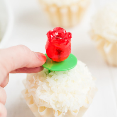 Coconut cupcakes with coconut buttercream and coconut topping, with tulip-shaped ring pops for decoration.