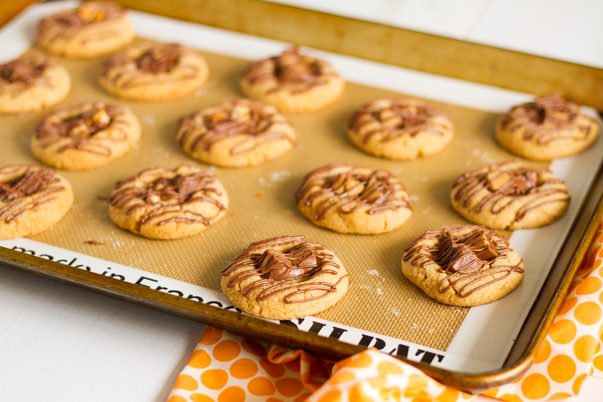 A classic peanut butter cookie with a twist! This delicious Candy Bar Thumbprint Cookies combine your favorite peanut butter cookie with chopped up candy bars and a drizzle of melted milk chocolate!