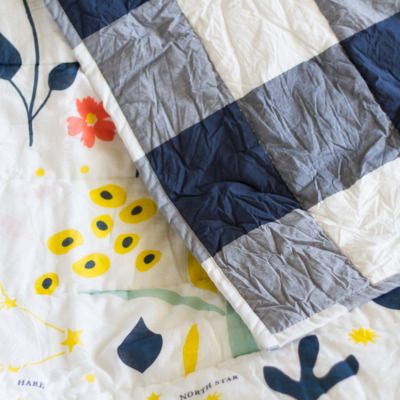 Cute bedding for a tween girl's bedroom, featuring navy buffalo check, flowers, and constellations.