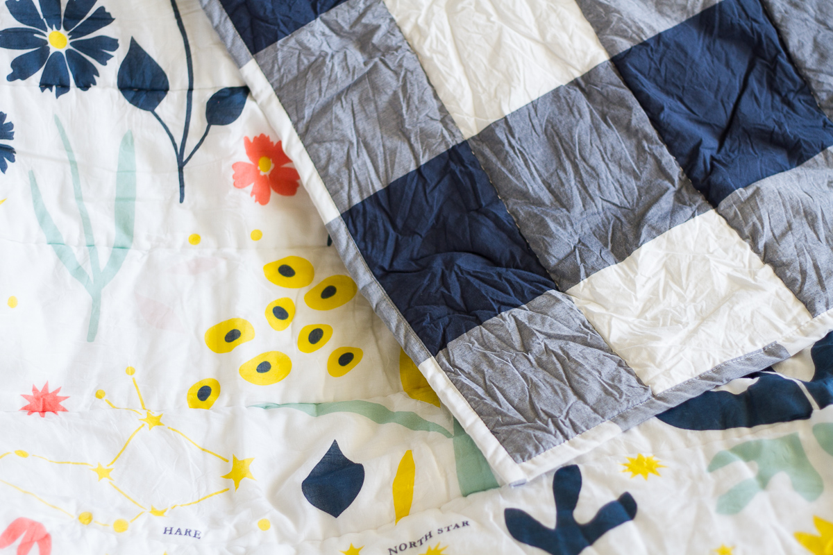 Cute bedding for a tween girl's bedroom, featuring navy buffalo check, flowers, and constellations.