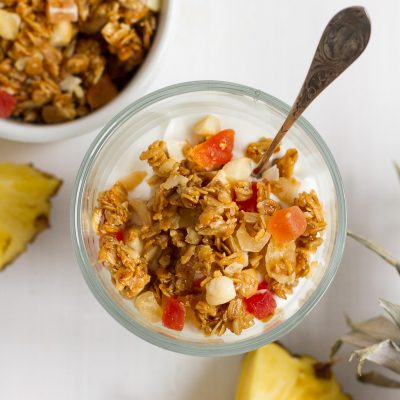 Crunchy homemade granola with oats, sunflower seeds, macadamia nuts, coconut chips, dried tropical fruits likes pineapple, mango, and papaya, lightly sweetened with honey and brown sugar.