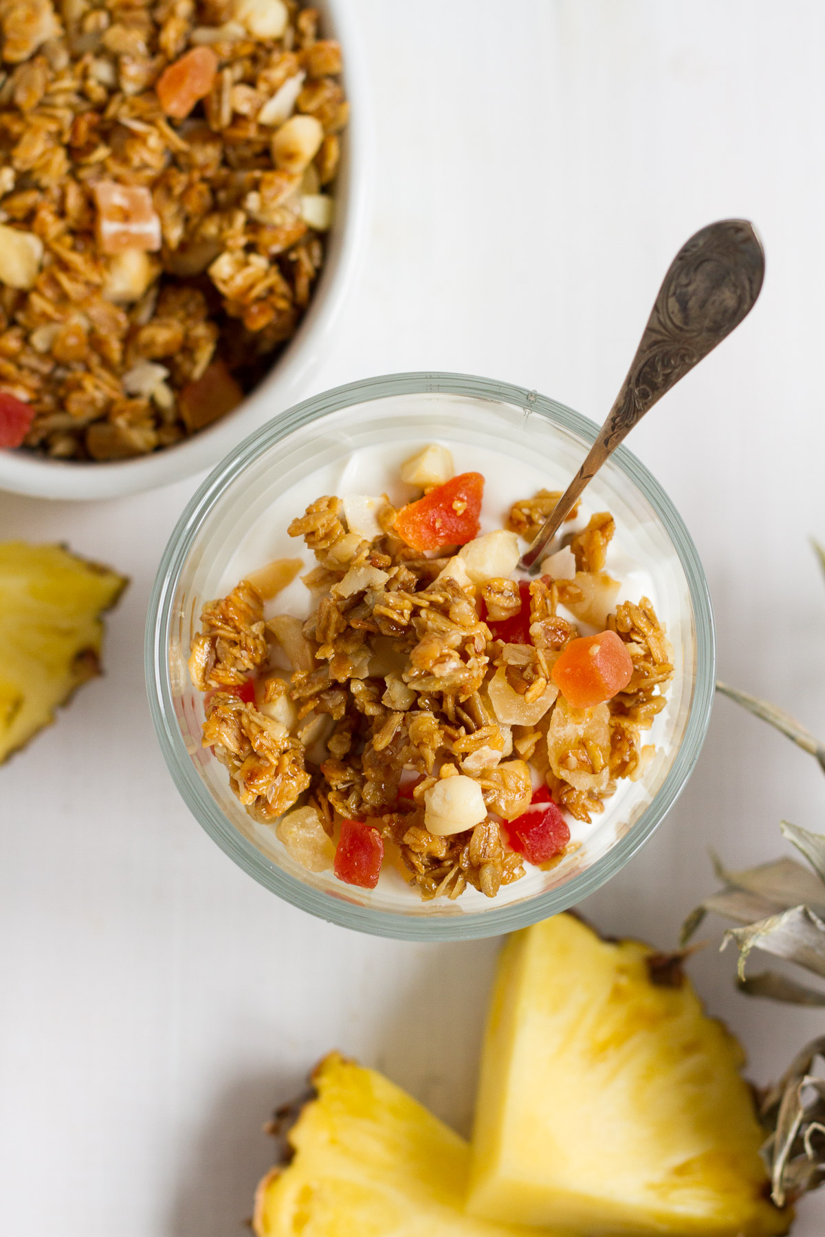 Crunchy homemade tropical granola with oats, sunflower seeds, macadamia nuts, coconut chips, dried tropical fruits likes pineapple, mango, and papaya, lightly sweetened with honey and brown sugar.