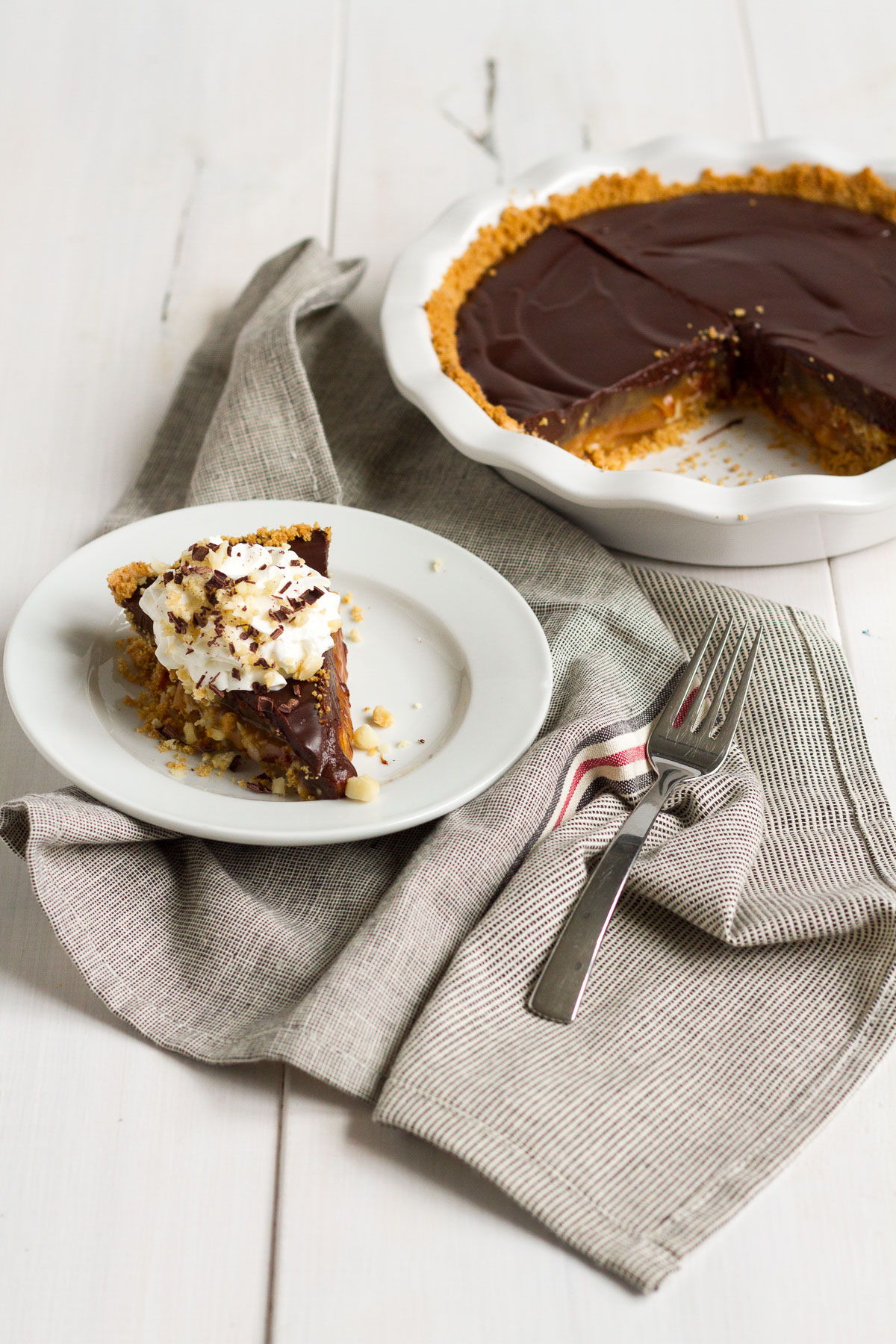 An over-the-top pie featuring a homemade graham cracker crust, a layer of macadamia nut-filled caramel, and a topping of rich chocolate ganache.