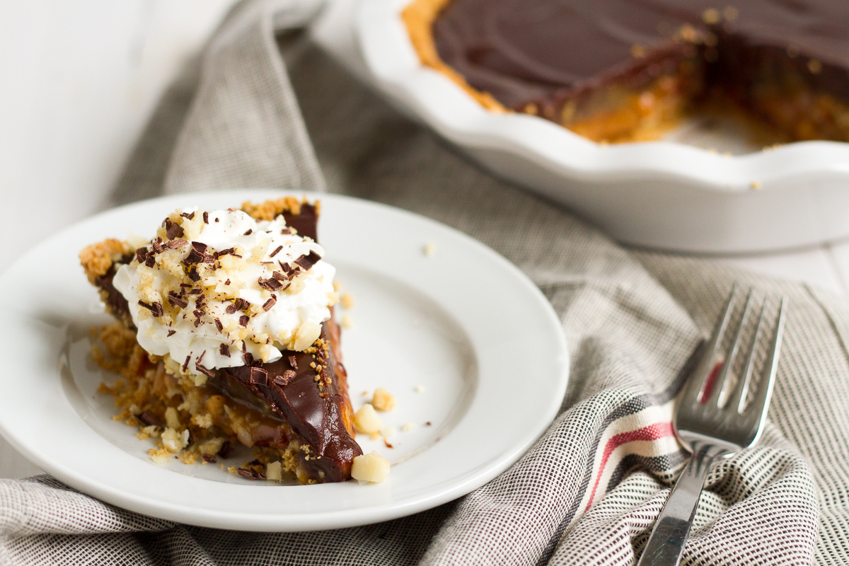 An over-the-top pie featuring a homemade graham cracker crust, a layer of macadamia nut-filled caramel, and a topping of rich chocolate ganache.