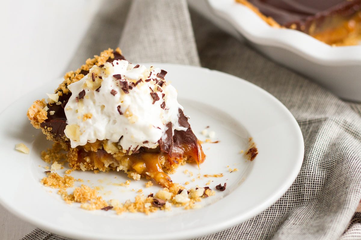 An over-the-top pie featuring a homemade graham cracker crust, a layer of macadamia nut-filled caramel, and a topping of rich chocolate ganache.