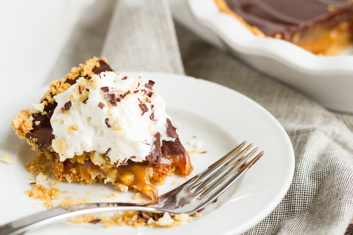 An over-the-top pie featuring a homemade graham cracker crust, a layer of macadamia nut-filled caramel, and a topping of rich chocolate ganache.