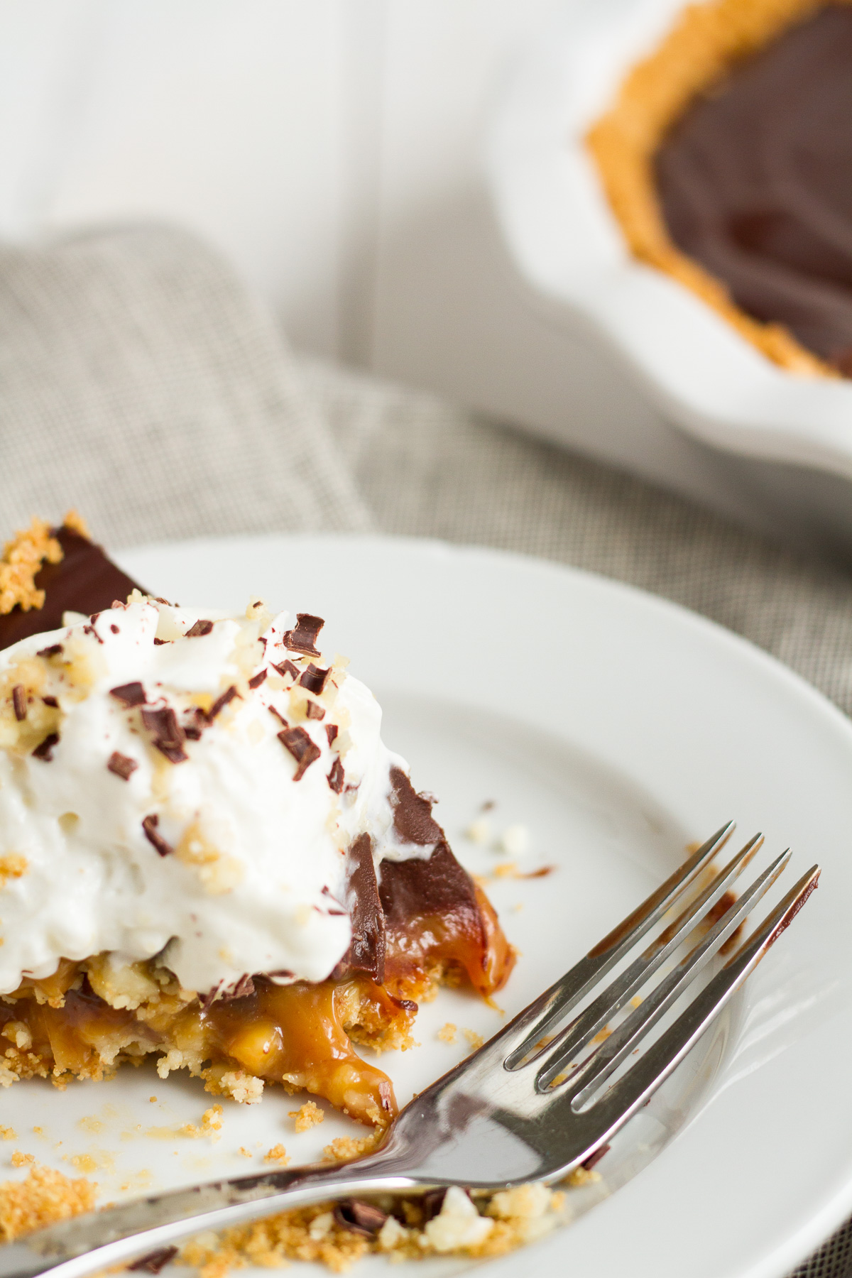 An over-the-top pie featuring a homemade graham cracker crust, a layer of macadamia nut-filled caramel, and a topping of rich chocolate ganache.