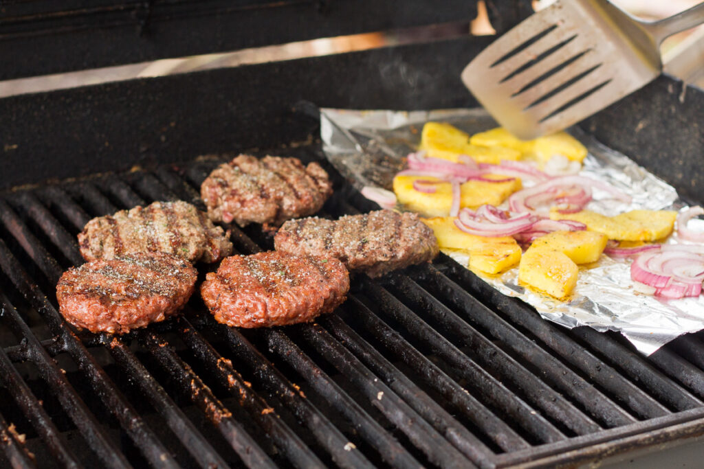 grilling beef and beyond burger patties along with pineapple and red onion slices for tropical bbq burgers