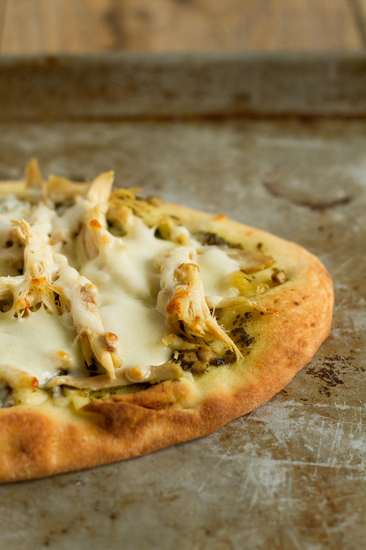 Flatbread pizza with pesto, cheese, and chicken.