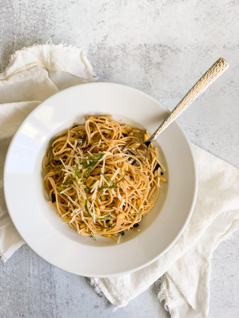 Overhead shot of lemon garlic spaghetti with parmesan cheese, pine nuts, and basil